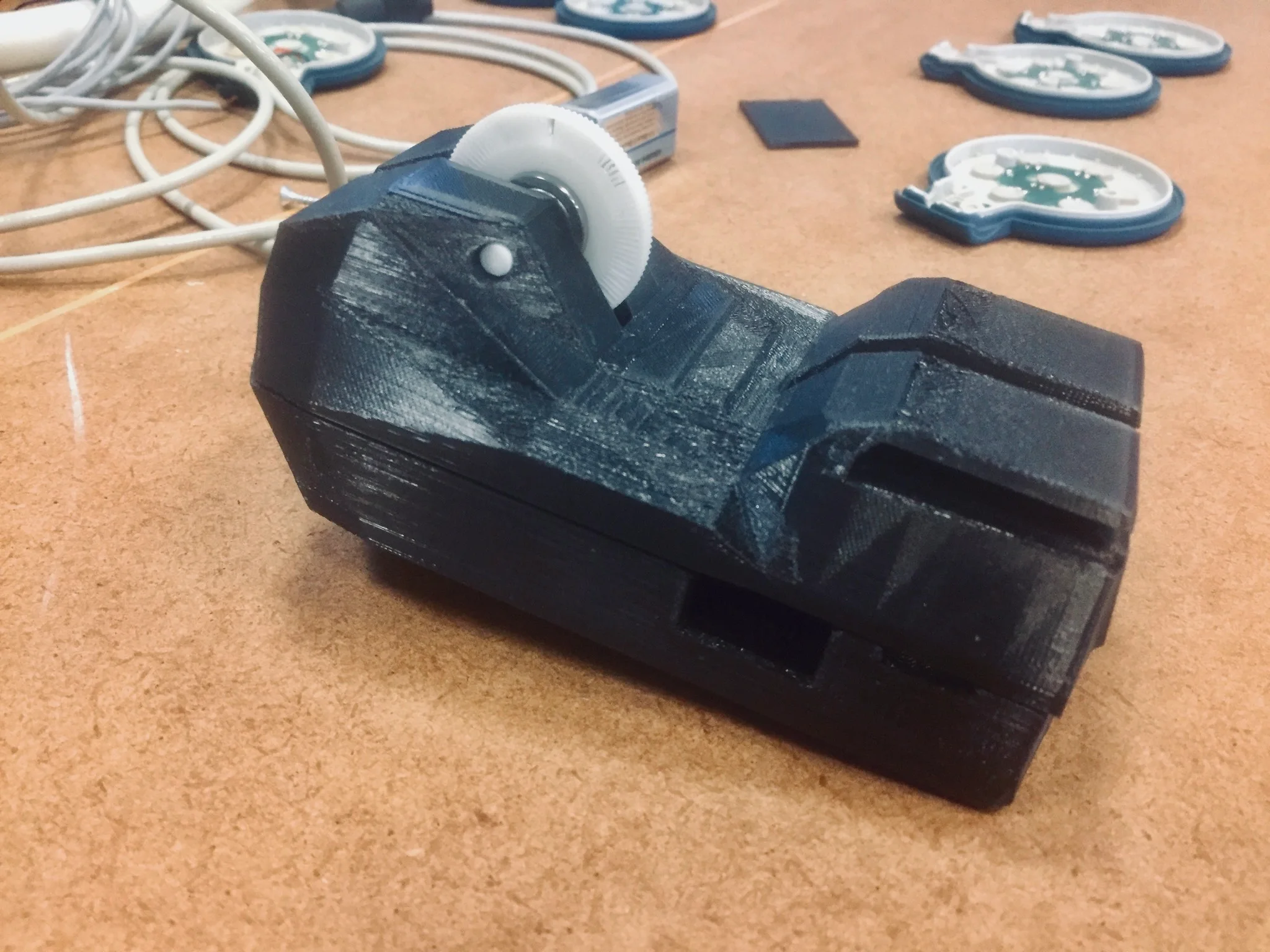 Schwarz 3D-gedruckter Geräte-Prototyp mit weißer Messrolle auf der Werkbank